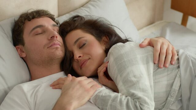Man woman couple lying together on bed bedroom sleeping home comfortable cozy hugging eyes closed slumber nap relaxing rest daydream sweetheart honeymoon affectionate tenderness cuddle beloved embrace
