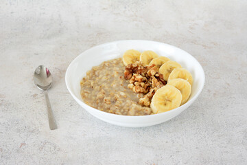 a bowl of oatmeal with bananas and a spoon next to it