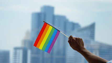 Office building background with a rainbow gay pride flag on the senior man's hand in the business...