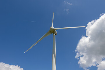 Der Rotorkopf eines Windrades ragt imposant in den blauen Himmel, symbolisiert moderne...