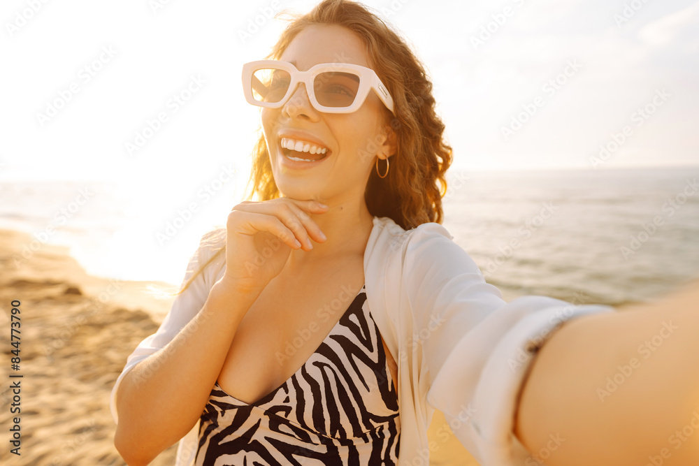 Wall mural Portrait of young  woman using smart phone selfie live on the beach. Happy girl online influencer blogger touch. Technology connected. Travel, weekend, relax and lifestyle concept.