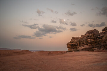 Outdoor Landscape in Wadi Rum with Sandstone Rock, Sandy Ground and Moon in Jordan. Beautiful Evening Desert Scenery in the Middle East.