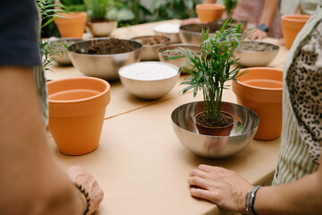replanting a houseplant workshop. Unrecognizable people in aprons stand near a table with plants, pots and soil mixture before the start of eco no-stress hobby master class 