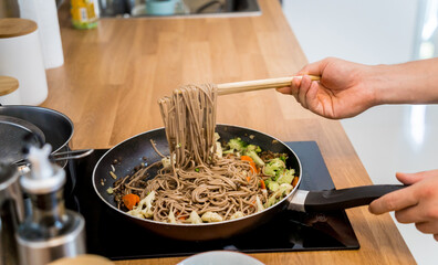 Chef at the kitchen preparing japanese buckwheat pasta with lentils