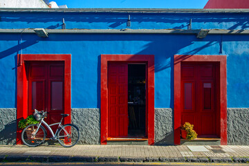 Buildings, street and parked bicycle on blue sky background. Colonial style of the city. Houses...