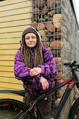 European stylish woman in an informal look with dreadlocks and piercings moves around the city on a...