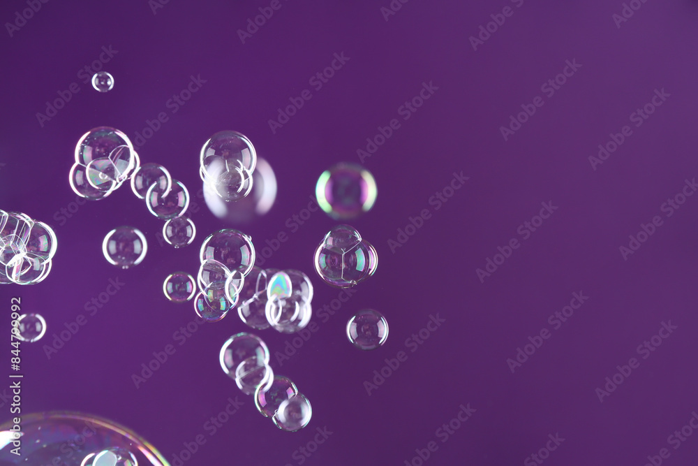 Poster Beautiful transparent soap bubbles on purple background, space for text