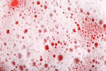 White foam with bubbles on red background, top view