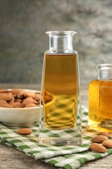 Almond oil in bottles and nuts on wooden table, closeup