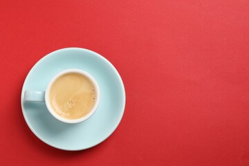 Aromatic coffee in cup on red background, top view. Space for text