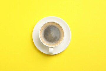 Aromatic coffee in cup on yellow background, top view