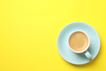 Aromatic coffee in cup on yellow background, top view. Space for text