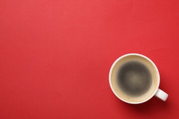 Aromatic coffee in cup on red background, top view. Space for text