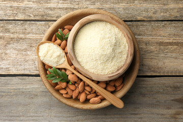 Fresh almond flour, spoon, branches and nuts on wooden table, top view
