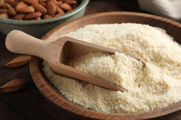 Fresh almond flour and scoop in bowl on table, closeup