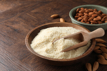Fresh almond flour, scoop in bowl and nuts on wooden table, closeup. Space for text