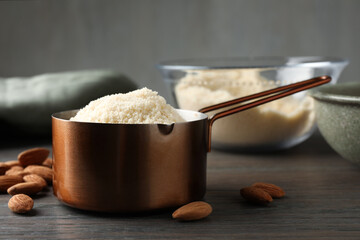Fresh almond flour in scoop and nuts on wooden table, closeup