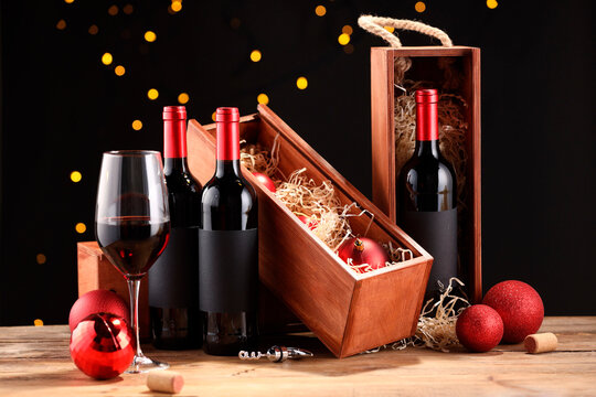 Bottles of wine, glass, wooden boxes, corks and red Christmas balls on table