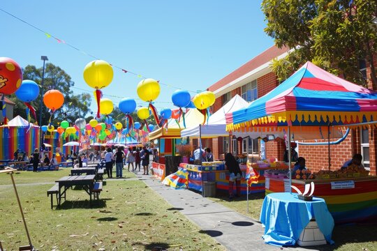 Community School Carnival Fundraiser with Colorful Games, Food Stalls, and Activities Under Clear Blue Sky - Powered by Adobe