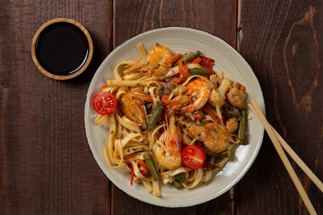 shrimp and udon vegetables pad thai sauce and chopsticks for and on the table