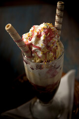 Copa de helado con vainilla por encima sirope de fresa y barquillos
