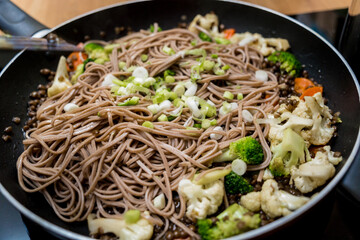 Chef at the kitchen preparing japanese buckwheat pasta with lentils