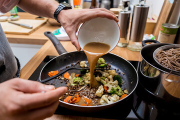 Chef at the kitchen preparing japanese buckwheat pasta with lentils