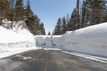 Road closed signs are buried deep in a wall of snow making a road impassable in the high sierras