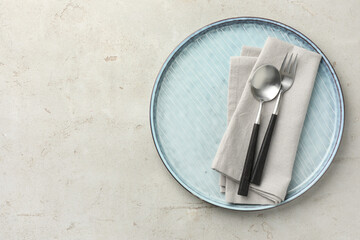 Stylish setting with cutlery, napkin and plate on light grey table, top view. Space for text
