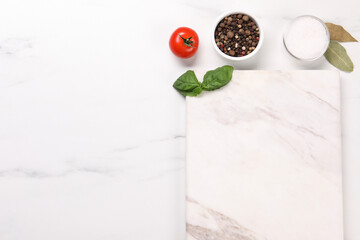 Cutting board, spices and tomato on white marble table, flat lay. Space for text