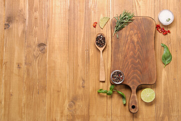 Cutting board, spices and lime on wooden table, flat lay. Space for text