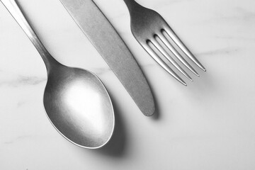 Stylish silver cutlery set on white marble table, flat lay