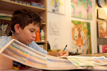 Naklejka premium Young boy focused on drawing during art class in a creative workshop
