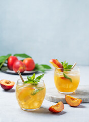 Two glasses with peach cocktail, lemonade or iced tea on a light background.