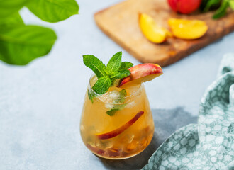 Refreshing peach cocktail, lemonade or iced tea on a light background with shadow.
