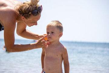 woman, mother applies sunscreen to the child. protection from the sun.