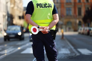 Policjant drogówki z lizakiem do zatrzymywania pojazdów kontroluje ruch drogowy. Tarcza.  © FotoDax