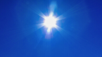 Obraz premium Bright sun shining in a clear blue sky, radiating light and warmth on a sunny day.