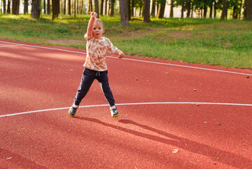 Fototapeta premium a little boy throws a basketball into a basket on the court, jumping up and down