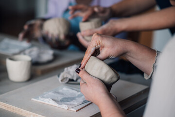 Close up of course attendee's hands modeling clay mug on pottery class