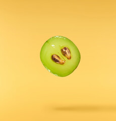 Fresh green grape falling in the air isolated on yellow background. High resolution image.