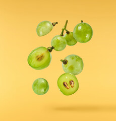 Fresh green grape falling in the air isolated on yellow background. High resolution image.