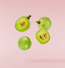 Fresh green grape falling in the air isolated on pink background. High resolution image.