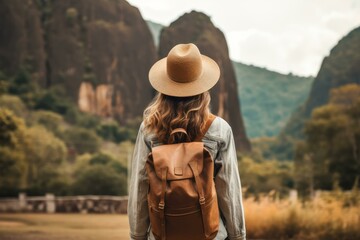 Naklejka premium Solo traveler with hat standing before stunning mountainous scenery