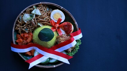 Tumpeng Merah Putih, yellow cone shaped  rice with red and white flag served during Indonesia Independence day every August 17, isolated black background copy space