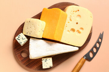 Wooden board with tasty cheese on beige background