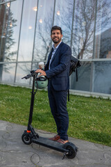 Businessman with Backpack Holds Electric Scooter and Takeaway Coffee in Financial District at Dawn