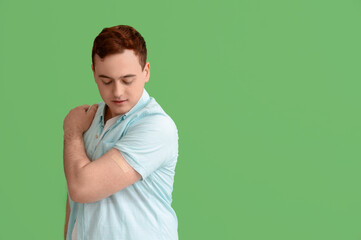 Young man with applied medical patch on green background. Vaccination concept