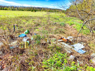 Garbage and debris litter the ground of a grassy meadow, highlighting the problem of pollution in natural environments