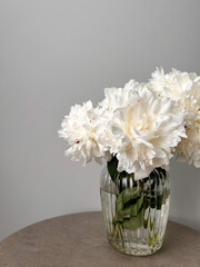 Bouquet of white peonies in a vase. The scent of flowers in the house. Flowers in the interior